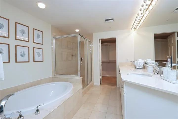 Bathroom featuring shower with separate bathtub, tile flooring, and double sink vanity