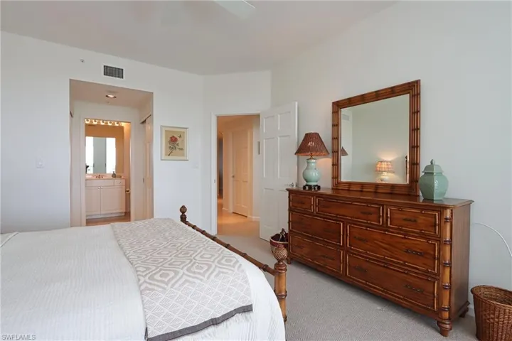 Bedroom with ceiling fan, connected bathroom, and light colored carpet