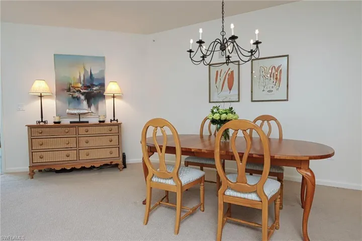 Carpeted dining room featuring a notable chandelier
