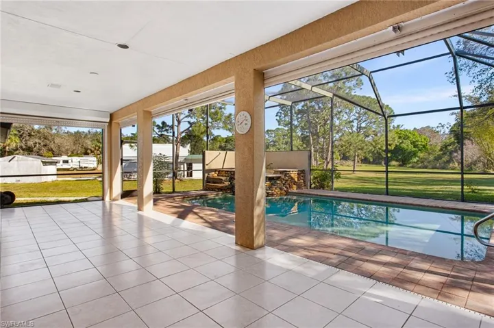 Screened lanai featuring a rectangular pool with integrated waterfall and stone accents