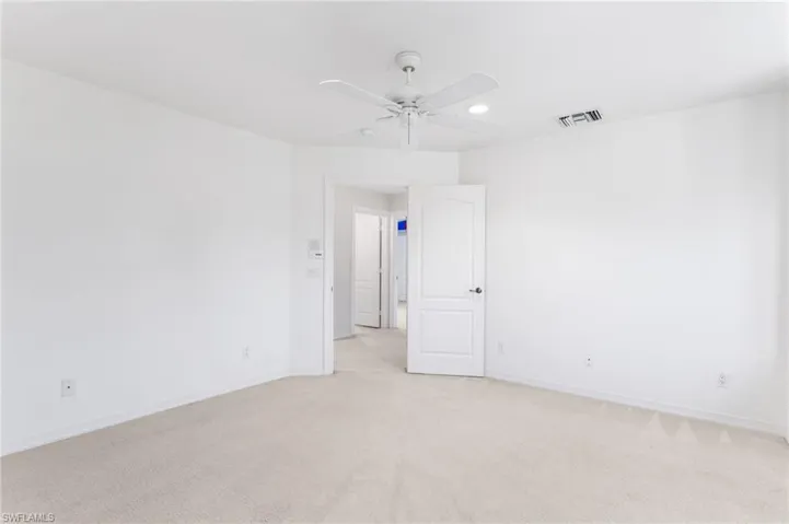 Carpeted room with a ceiling fan, recessed lighting, and a white paneled door