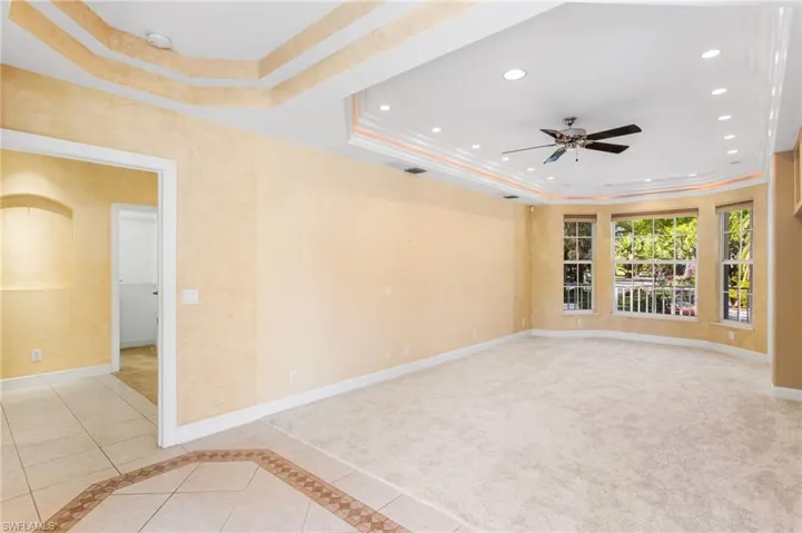 Spacious room featuring a tray ceiling with recessed lighting, a ceiling fan, and carpeted flooring