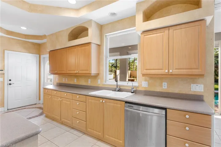 Kitchen featuring light wood cabinetry, a dual-basin sink, and a built-in stainless steel dishwasher