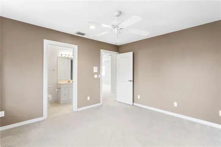 Carpeted room with neutral-toned walls, white trim, and a ceiling fan