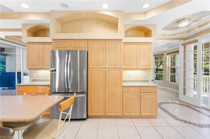 Kitchen featuring extensive wood cabinetry, a stainless steel refrigerator, and recessed lighting