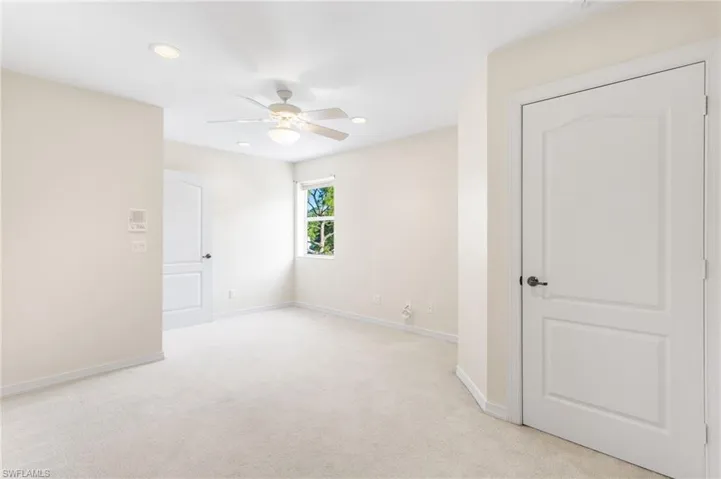 Carpeted interior space featuring light-colored walls and a ceiling fan with integrated lighting
