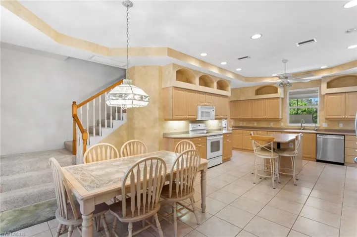 Kitchen featuring wood-finish cabinetry, tile flooring, recessed lighting, and a center island with seating