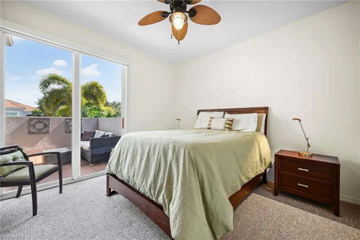 Bedroom featuring neutral-toned carpeting and a ceiling fan with woven blades