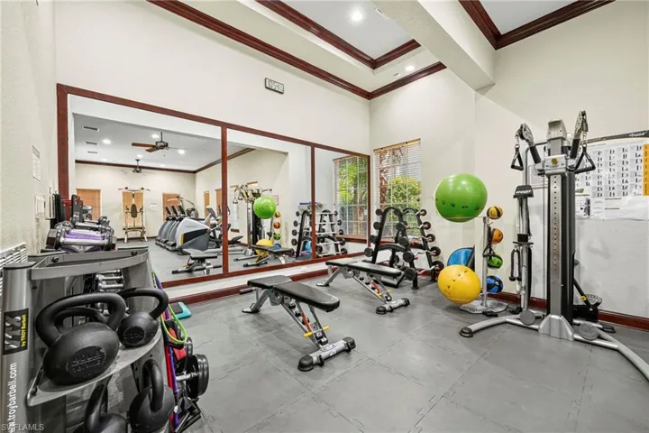 Dedicated fitness room featuring interlocking rubber floor tiles, a mirrored wall, and recessed ceiling lighting