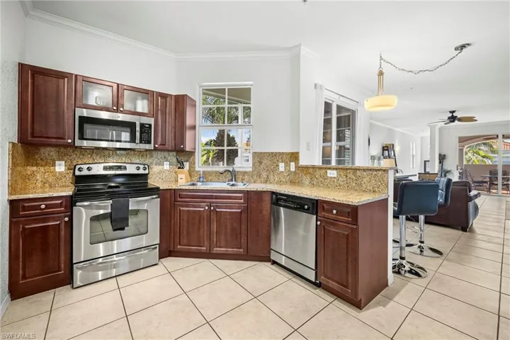 Kitchen featuring wood cabinetry, stainless steel appliances, speckled stone countertops, and a tile backsplash