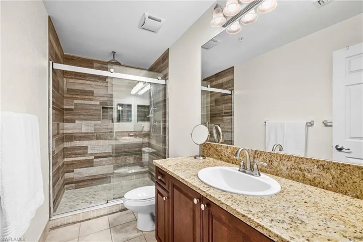 Bathroom featuring a wood-finish tile shower with clear glass sliding doors, a built-in shower niche, and a rain showerhead