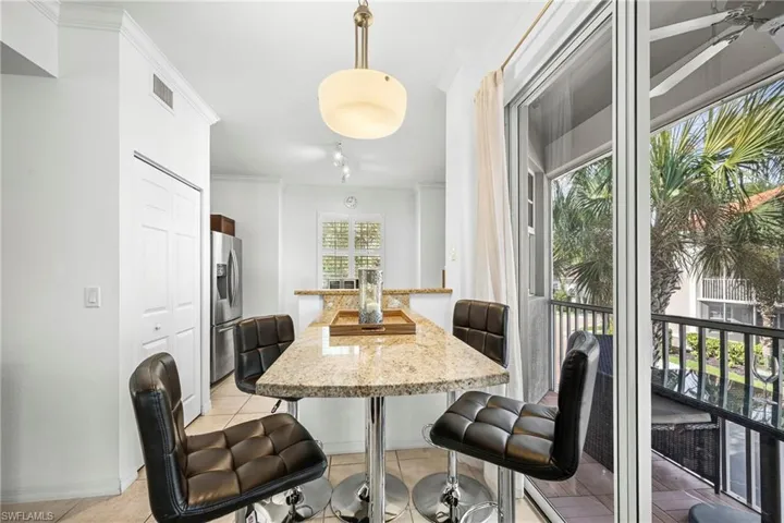 Kitchenette featuring a granite-look breakfast bar with pendant lighting, stainless steel refrigerator, and tiled flooring