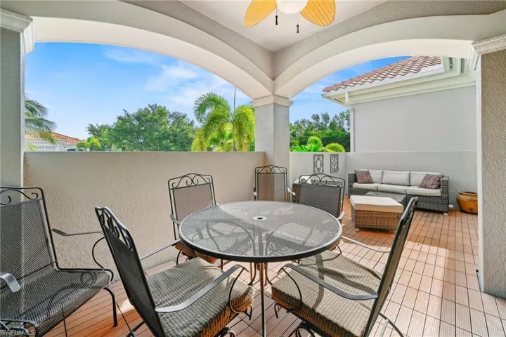 Spacious outdoor patio featuring wood-finish flooring, a ceiling fan, and arched architectural details