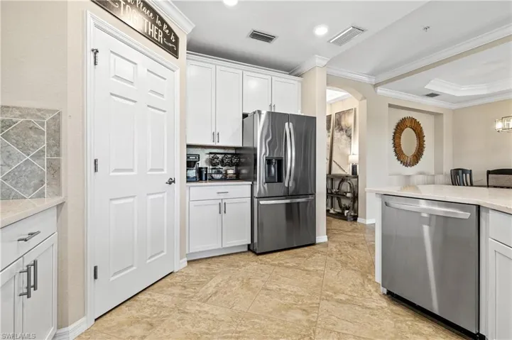 Stainless steel appliances, white cabinetry, light-toned tiled flooring, light-toned countertops, and recessed lighting