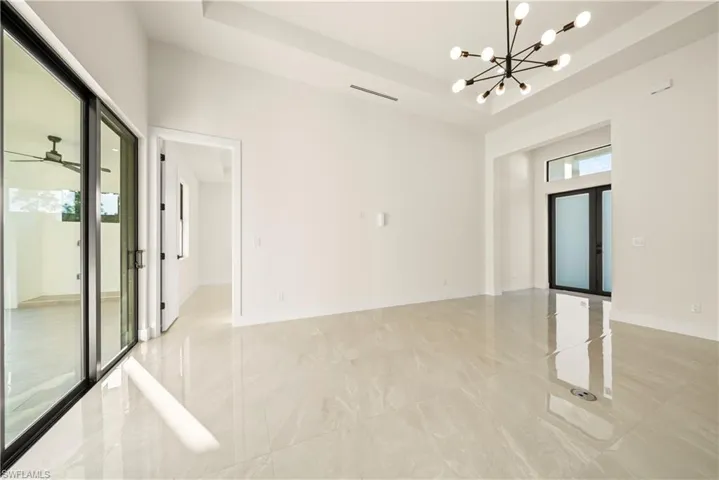 Empty room featuring a tray ceiling, a chandelier, a ceiling fan, and french doors