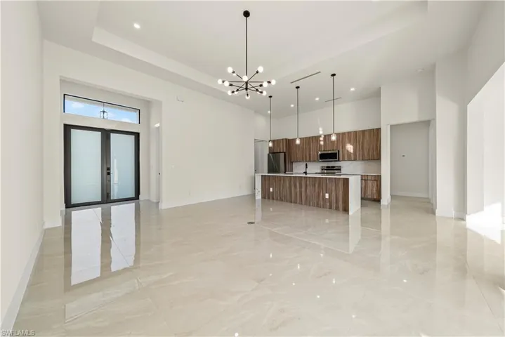 Kitchen with open floor plan, modern cabinets, a large island with sink, a chandelier, and wood finish cabinets