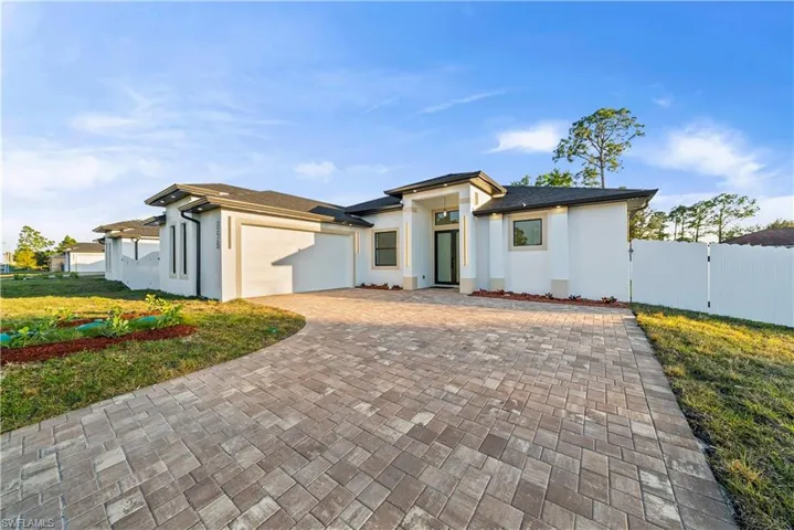 Prairie-style home with a gate, stucco siding, decorative driveway, and a garage