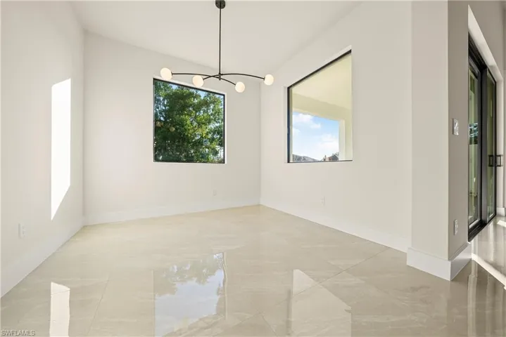 Unfurnished dining area with hanging lights and baseboards