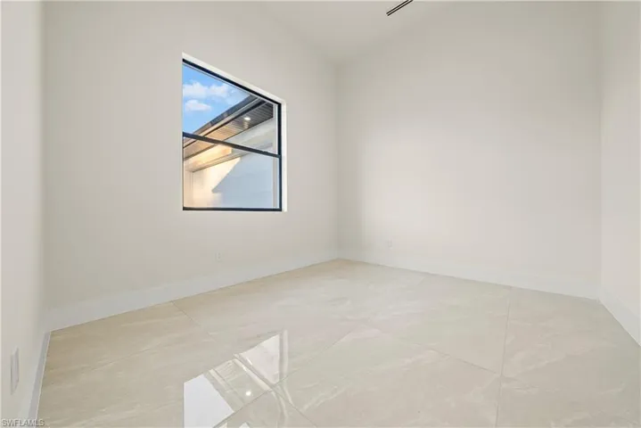 Spare room featuring lofted ceiling and baseboards