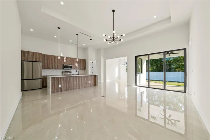 Kitchen with stainless steel appliances, hanging lights, open floor plan, modern cabinets, and a tray ceiling