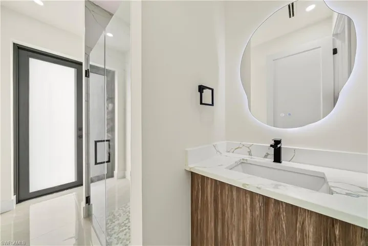 Bathroom featuring a marble finish shower, vanity, and recessed lighting