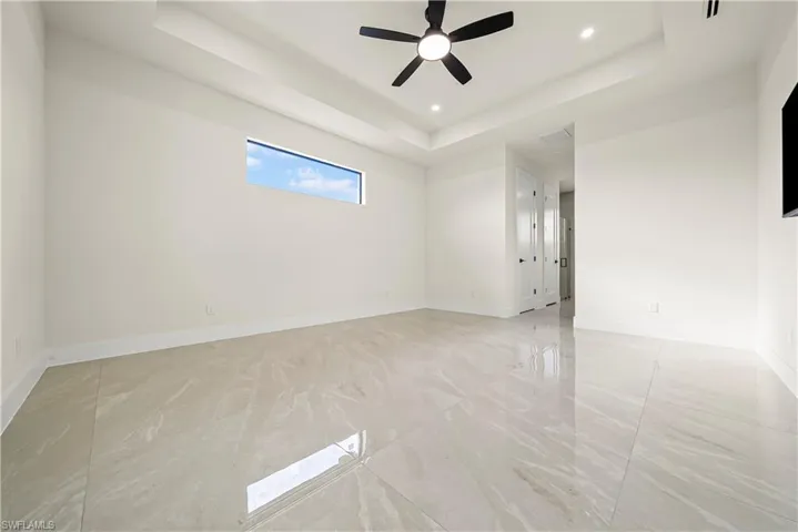 Empty room featuring a tray ceiling, a ceiling fan, and recessed lighting
