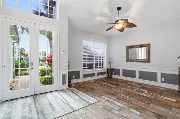 Doorway to outside with a decorative wall, french doors, hardwood / wood-style flooring, a ceiling fan, and wainscoting