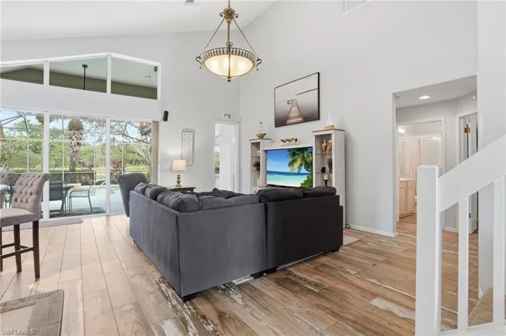 Living area featuring a sunroom, light wood-type flooring, and lofted ceiling