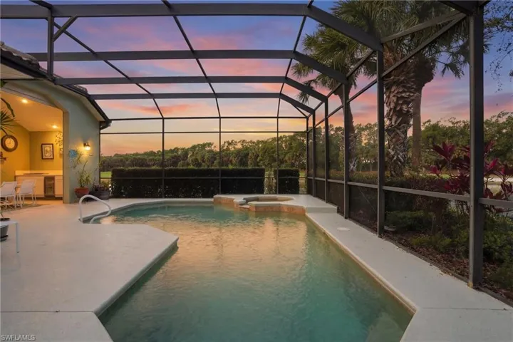 Pool at dusk featuring a pool with connected hot tub, a lanai, a sunroom, and a patio area
