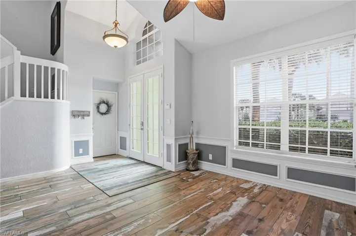 Foyer featuring french doors, light wood-style flooring, ceiling fan, wainscoting, and vaulted ceiling