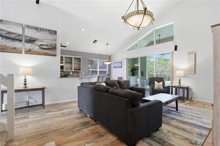 Living room featuring light wood-style floors, vaulted ceiling, and healthy amount of natural light