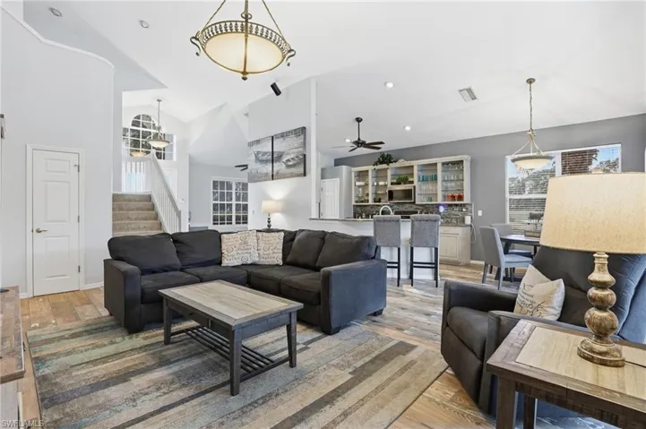 Living area with light wood-style floors, vaulted ceiling, and recessed lighting