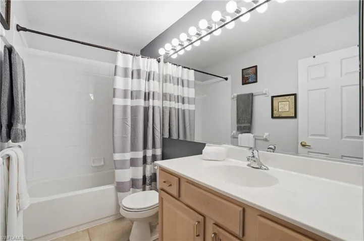 Full bath with vanity, shower / bath combination with curtain, and light tile patterned floors