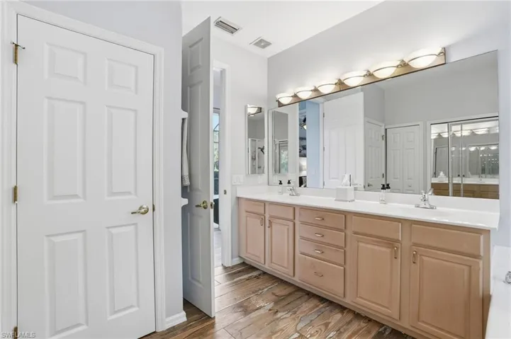 Full bathroom with double vanity, light wood-style flooring, and a closet