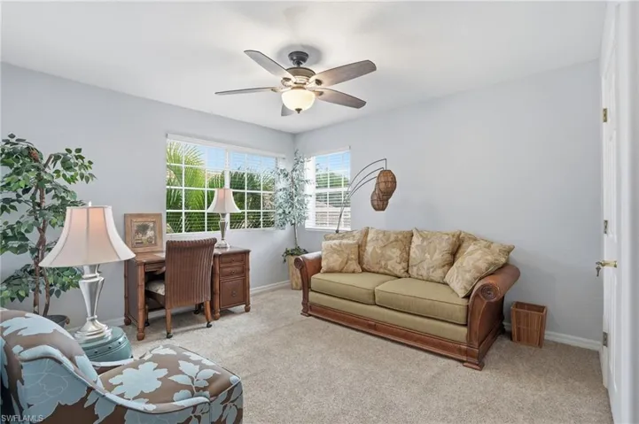 Living area featuring light colored carpet and a ceiling fan