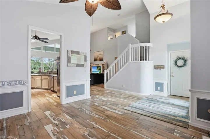 Unfurnished living room with a ceiling fan, a high ceiling, and light wood-style flooring