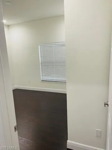 Spare room featuring baseboards and dark wood-style floors