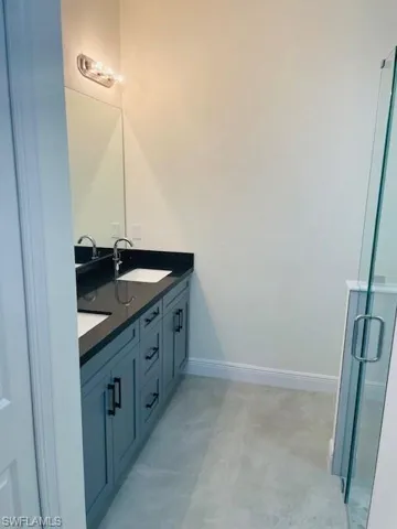 Full bathroom featuring double vanity and a shower stall