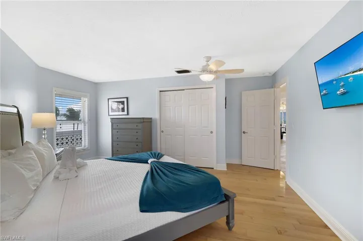 Bedroom featuring wood-finish flooring, light blue walls, and white trim - Virtually Edited Image