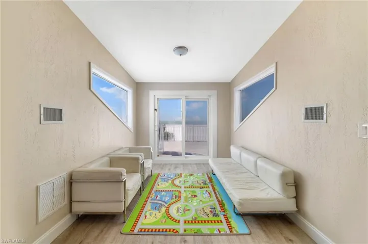 Room with two unique triangular windows and a sliding glass door leading to an outdoor deck - Virtually Edited Image
