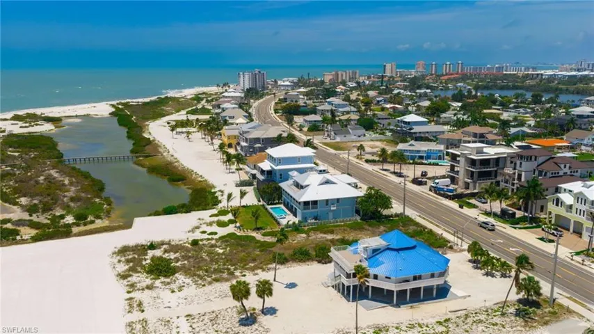 Coastal property with direct beach frontage and Gulf of Mexico access, featuring a light blue exterior, multiple balconies, and a metal roof - Virtually Edited Image