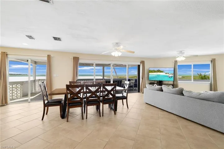Open-concept living space with light-toned tile flooring throughout - Virtually Edited Image