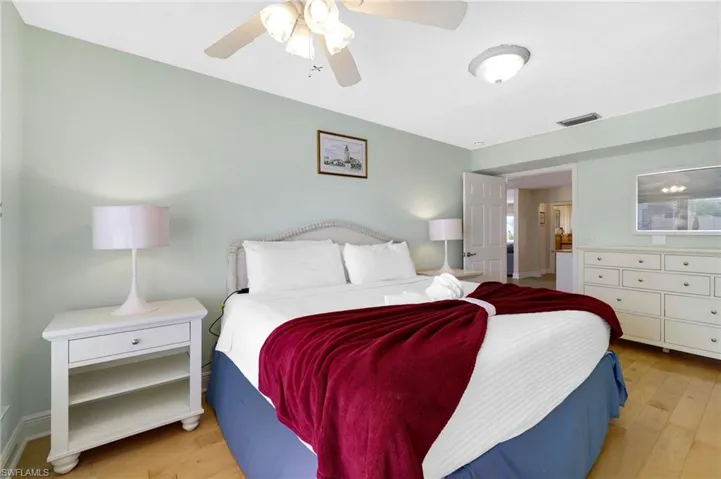 Spacious room featuring wood-finish flooring, light green walls, a white ceiling fan, and recessed lighting - Virtually Edited Image