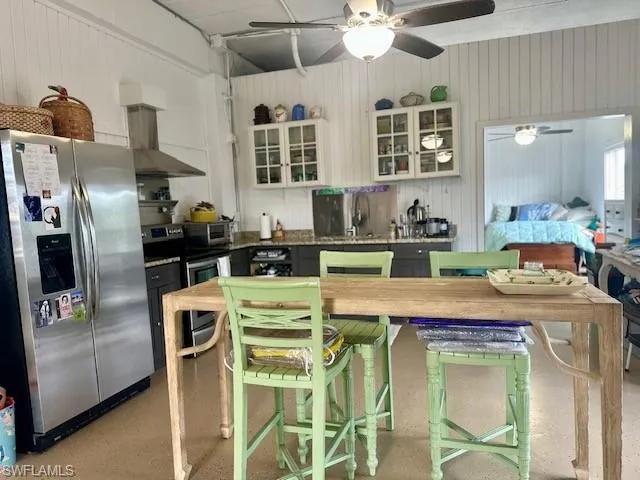 Two tone kitchen with dual tone cabinetry, stainless steel appliances, a ceiling fan, and glass fronted cabinets