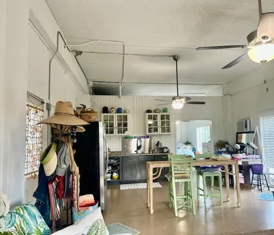 Kitchen with ceiling fan, freestanding refrigerator, concrete floors, and glass insert cabinets