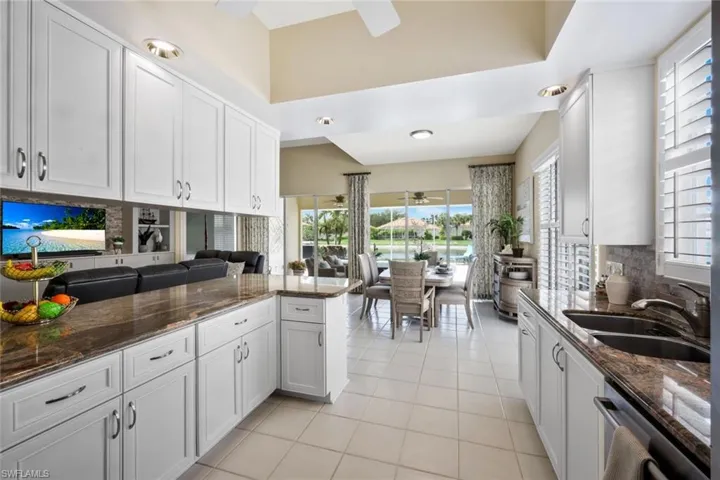 Open kitchen has ample, swirling granite countertops w/ dining area, pool & lake views in the background!