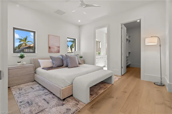 Bedroom with light wood-style flooring, a spacious closet, a ceiling fan, and connected bathroom