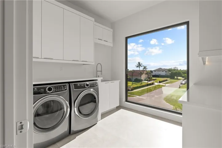 Laundry area featuring cabinet space, washer and clothes dryer, and a residential view