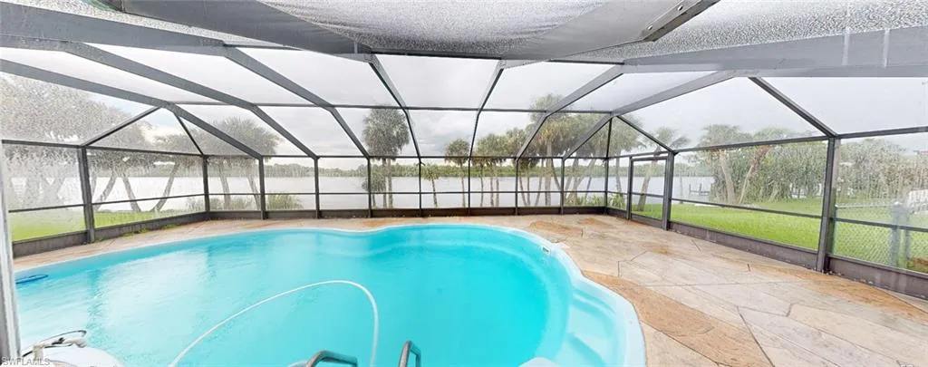View of swimming pool featuring glass enclosure and a patio area