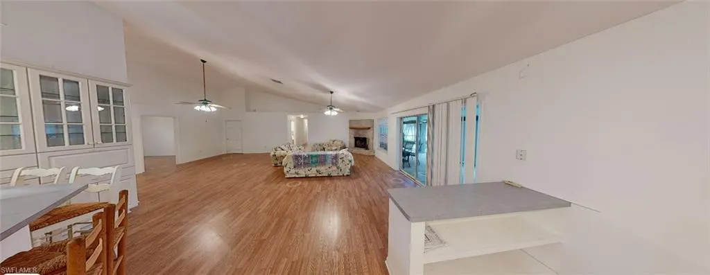 Living room with ceiling fan, vaulted ceiling, and light hardwood / wood-style floors